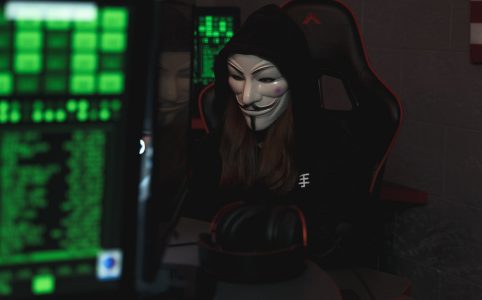 person with mask sitting while using a computer